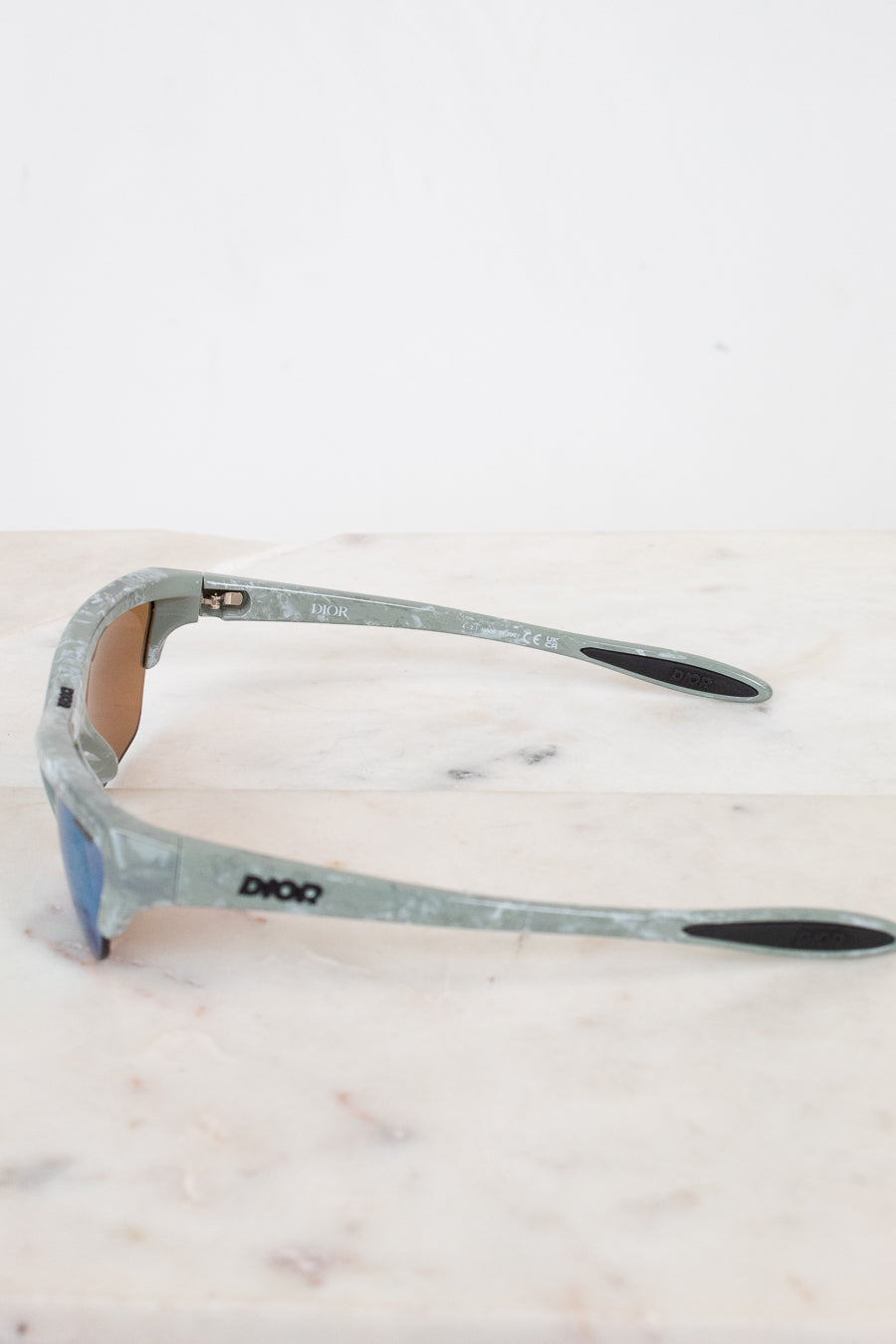 Sunglasses with a green and gray frame on a light marble background