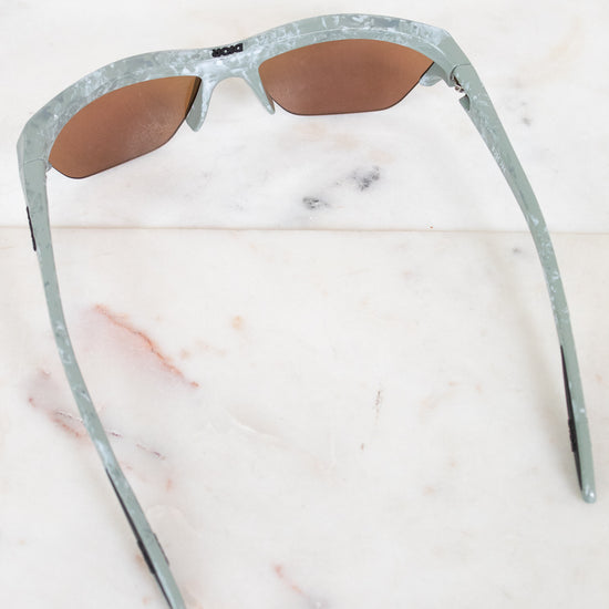 Sunglasses with a green and gray frame on a marble surface