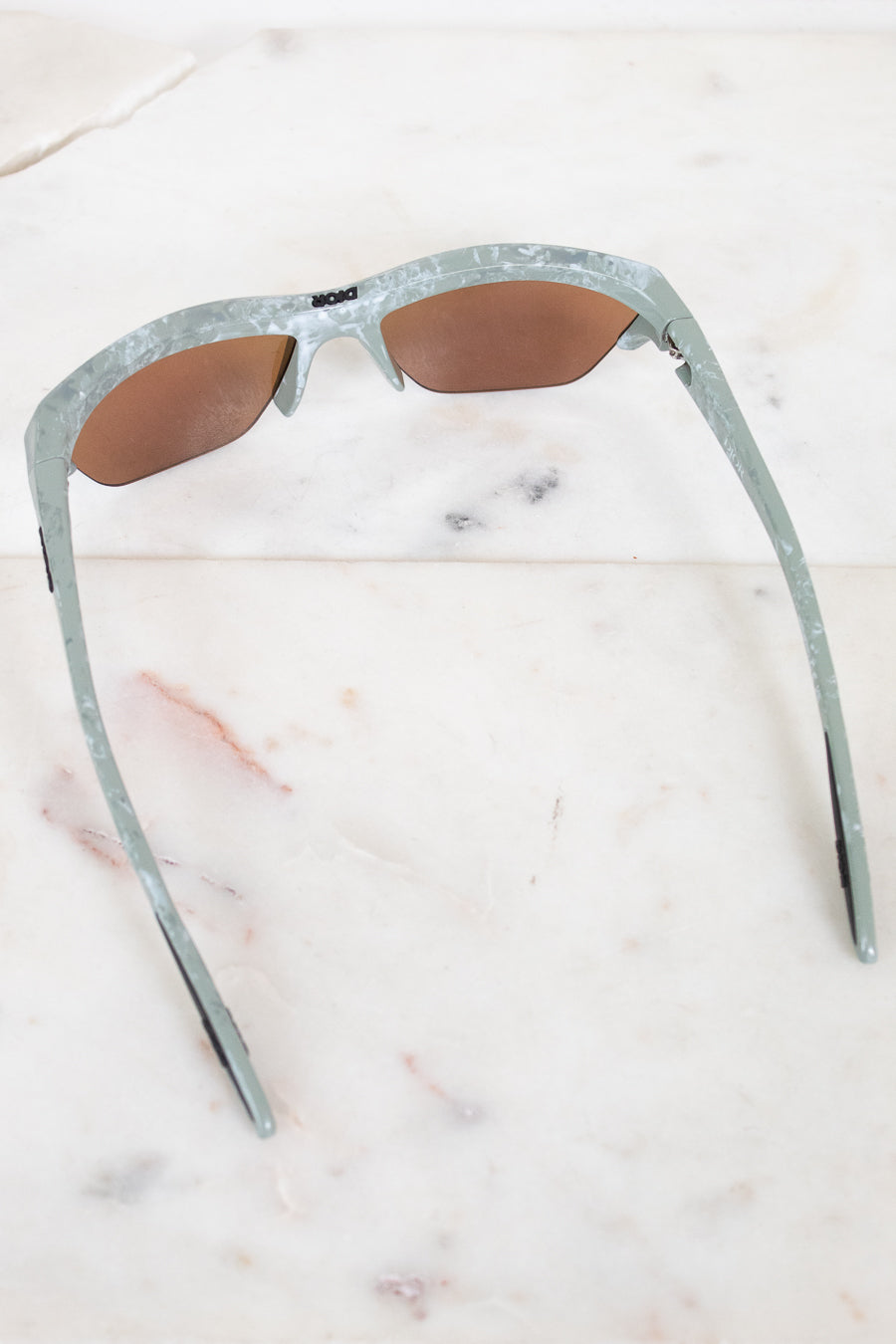 Sunglasses with a green and gray frame on a marble surface