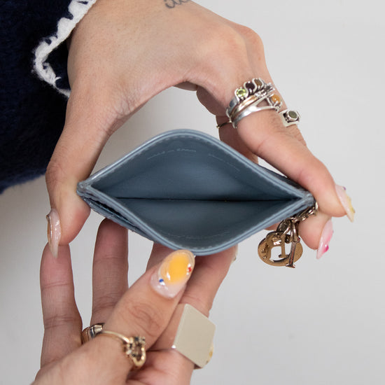 Hand holding a small blue cardholder  with a plain background