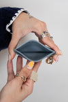 Hand holding a small blue cardholder  with a plain background