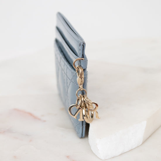 Close-up of charms attached to light blue card holder against a white background