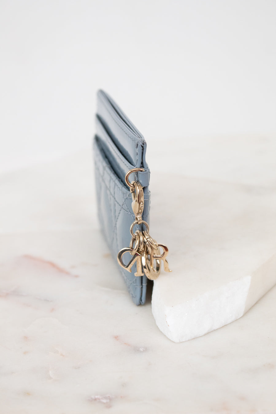 Close-up of charms attached to light blue card holder against a white background