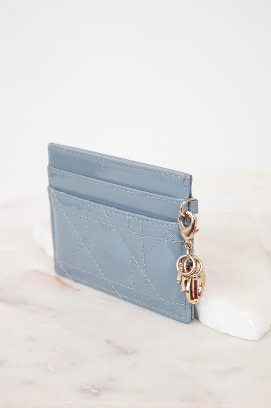 Card holder with gold charm details against white surface