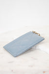 Light blue quilted card holder on a white marble surface