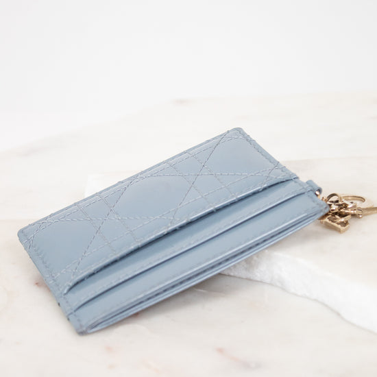 Light blue wallet with a chain on a white marble surface
