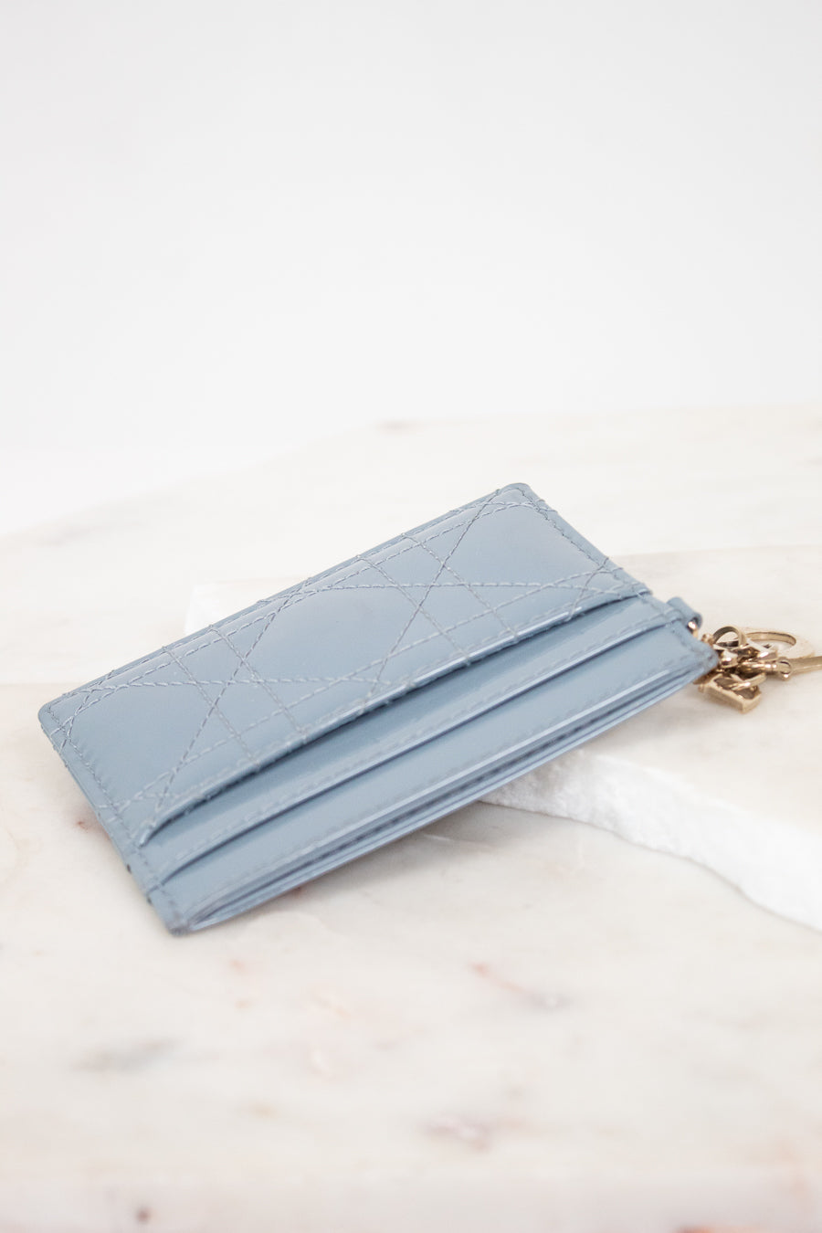Light blue wallet with a chain on a white marble surface