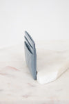 Side view of light blue card holder against marble surface