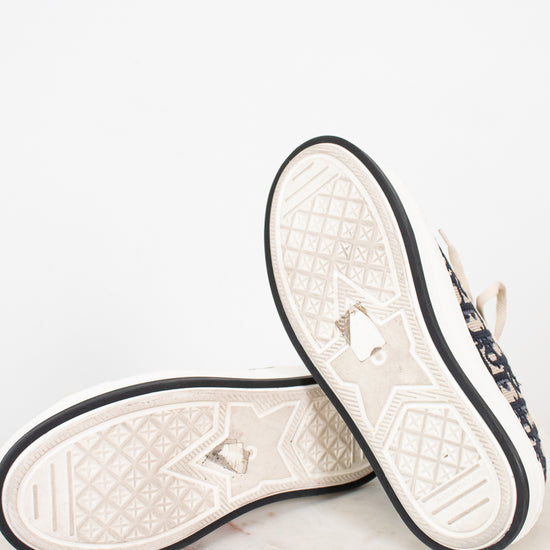 Pair of white and navy sneakers with black bordered soles on a light gray background