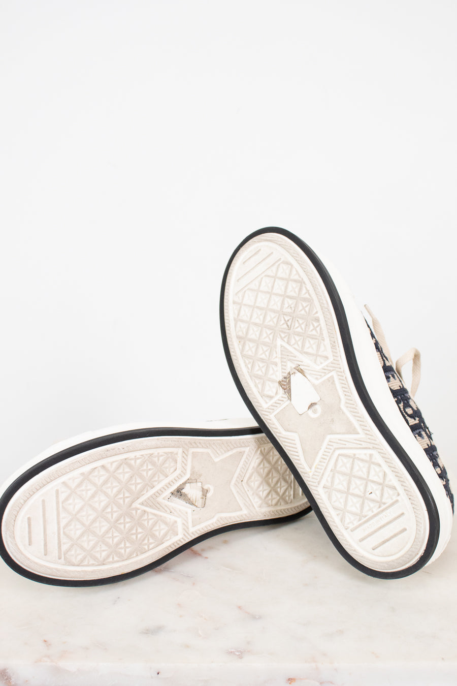 Pair of white and navy sneakers with black bordered soles on a light gray background