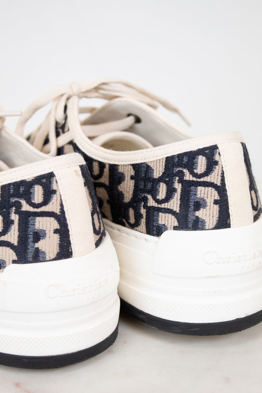 White sneakers with navy text pattern on a white background