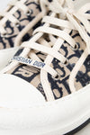 Close-up of white sneakers with Dior logo on a white background