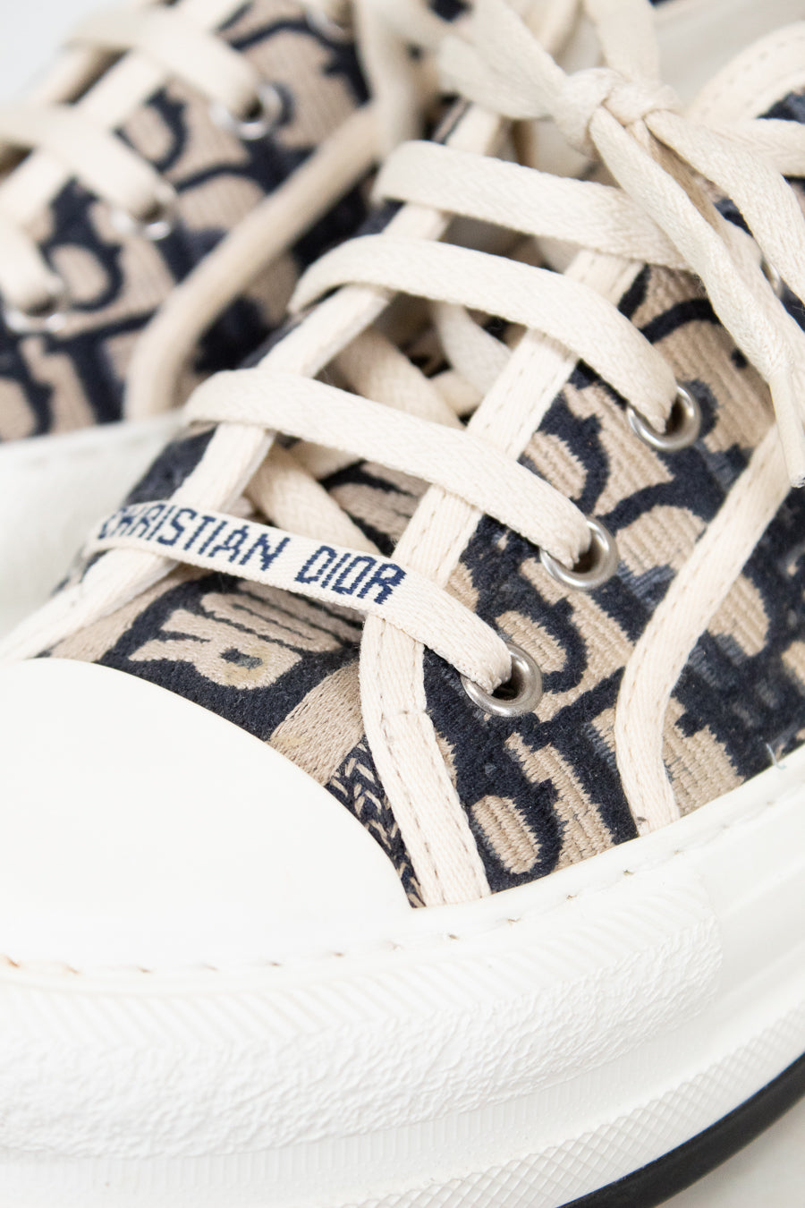 Close-up of white sneakers with Dior logo on a white background