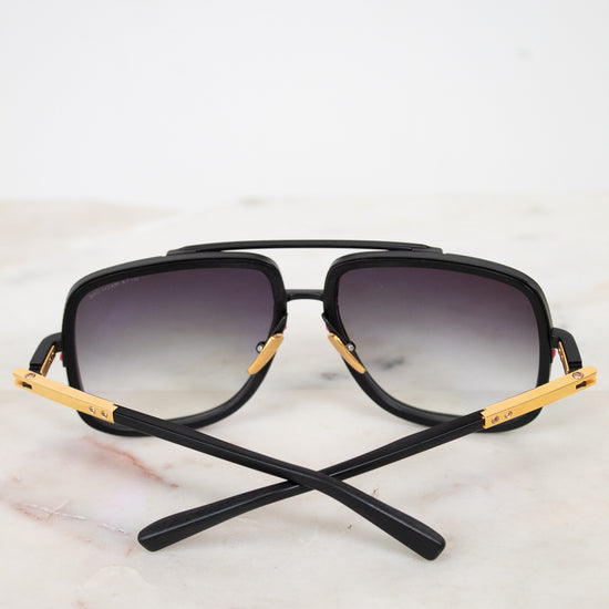 Black sunglasses with gold accents on a light marble background