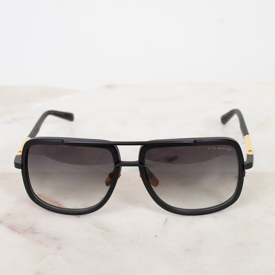 Black sunglasses with gold accents on a marble surface