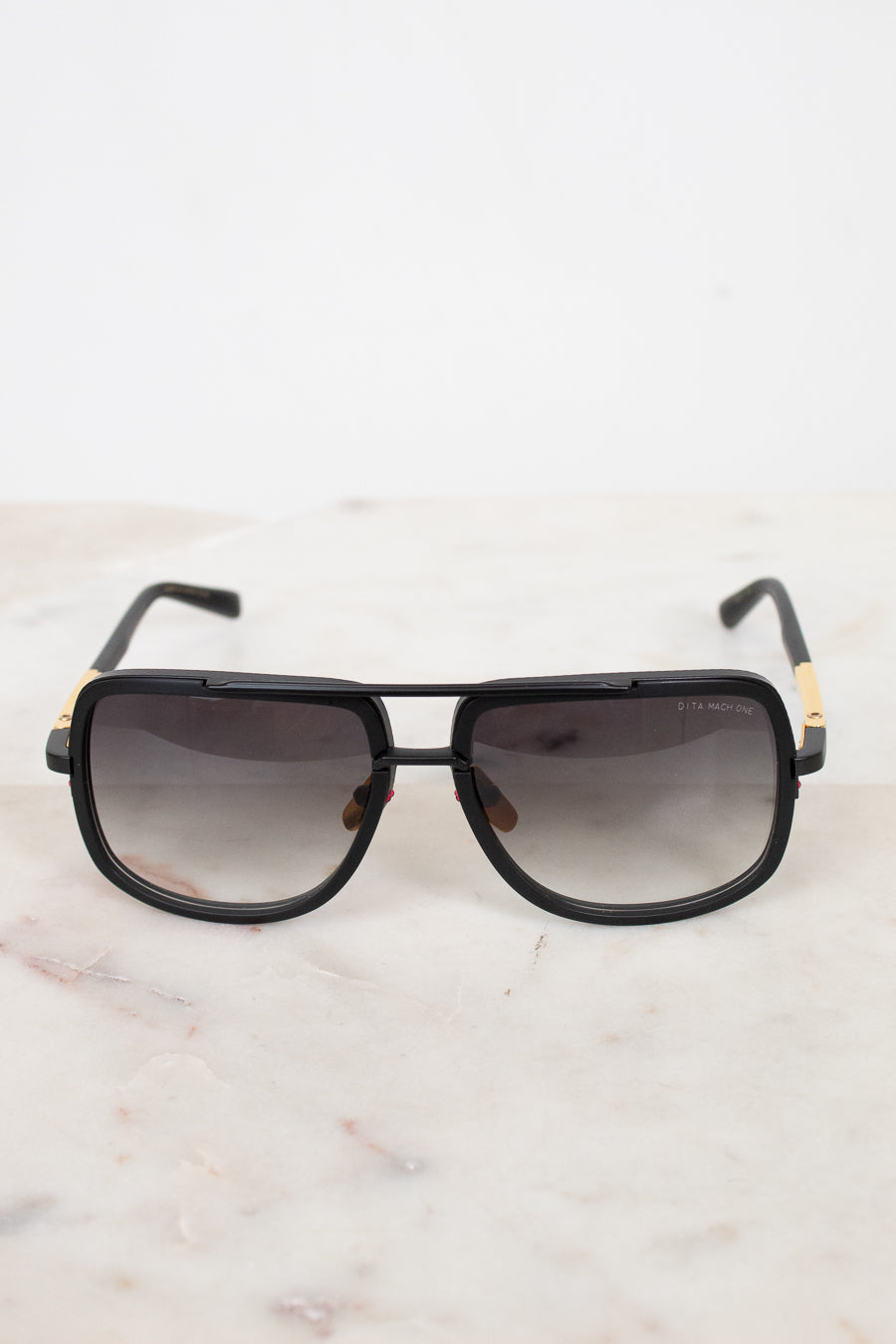Black sunglasses with gold accents on a marble surface