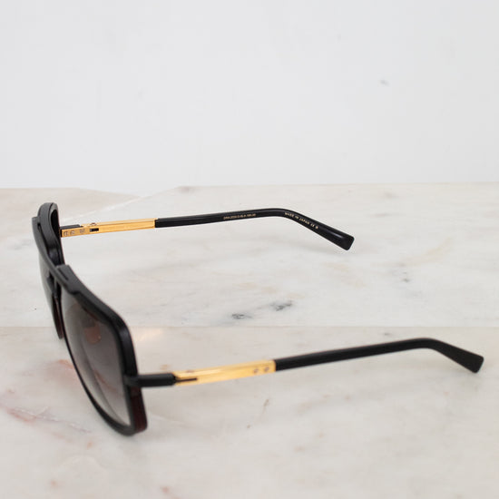 Black sunglasses with gold accents on a marble surface