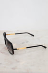Black sunglasses with gold accents on a marble surface
