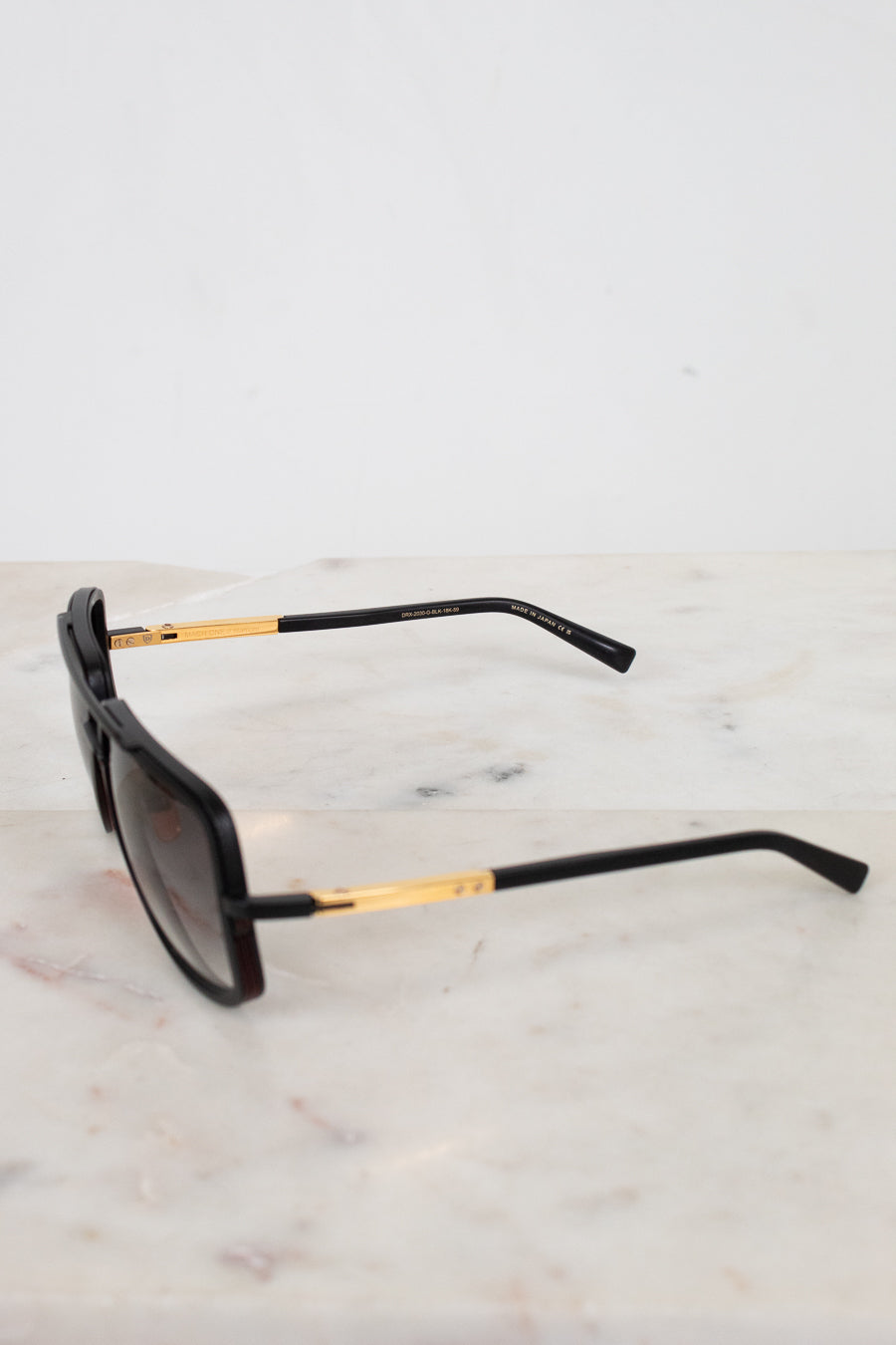 Black sunglasses with gold accents on a marble surface
