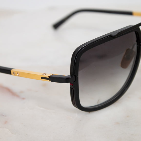 Sunglasses with black frame and gold accents on a marble surface