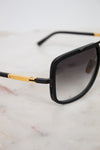 Sunglasses with black frame and gold accents on a marble surface