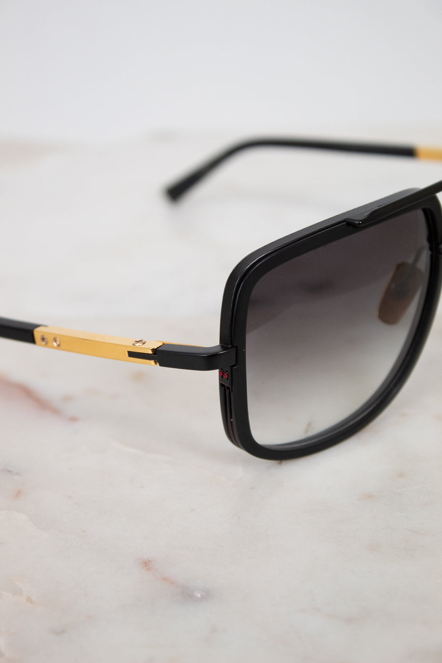 Sunglasses with black frame and gold accents on a marble surface