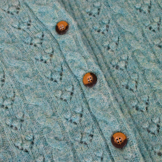 Close-up of a teal knitted garment with button details