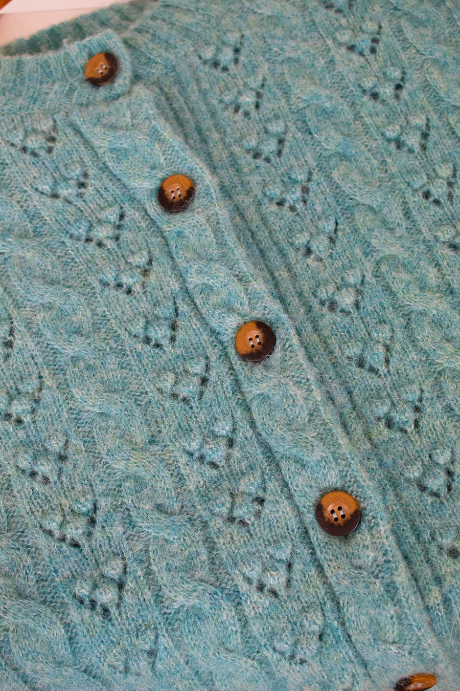 Close-up of a teal knitted garment with button details
