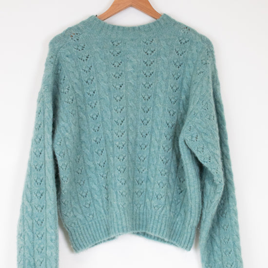 Teal sweater on a wooden hanger against a white background