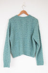 Teal sweater on a wooden hanger against a white background