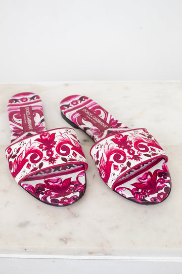 Pair of pink and white patterned slide sandals  on a light marble surface