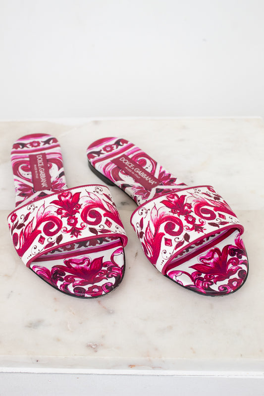Pair of pink and white patterned slide sandals  on a light marble surface