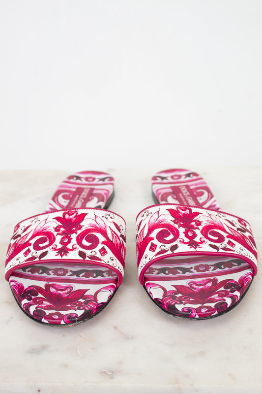 Pair of pink and white patterned slides on a marble surface
