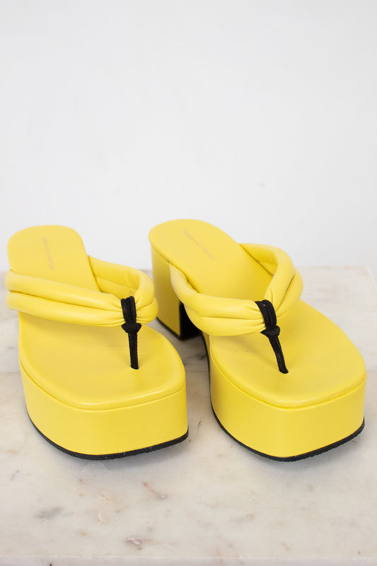 Yellow platform sandals with black straps on a light background