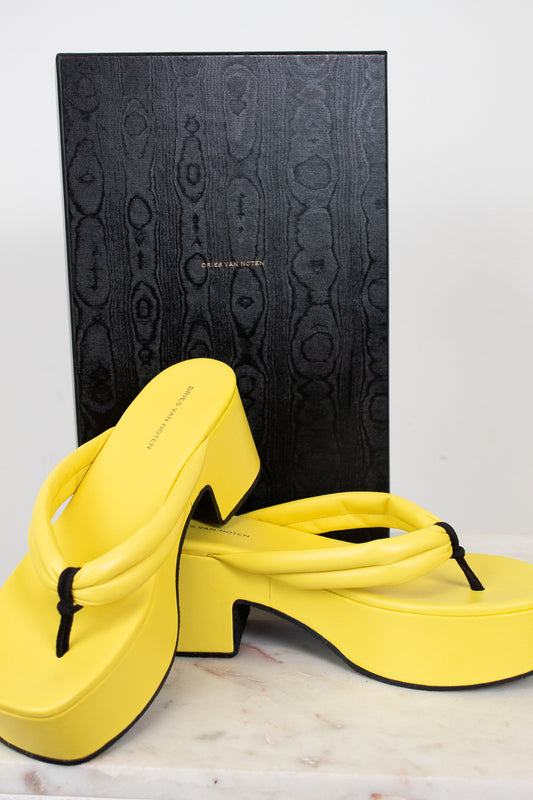 Yellow sandals with a black box on a light background