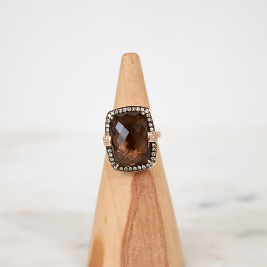 Ring with a smoky top stone on a wooden stand against a white background