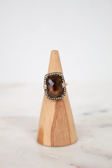 Ring with a smoky top stone on a wooden stand against a white background