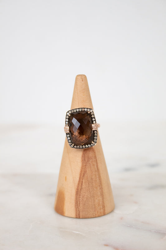 Ring with a smoky top stone on a wooden stand against a white background