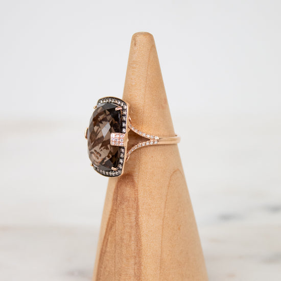 Ring with a brown gemstone on a wooden cone against a light background