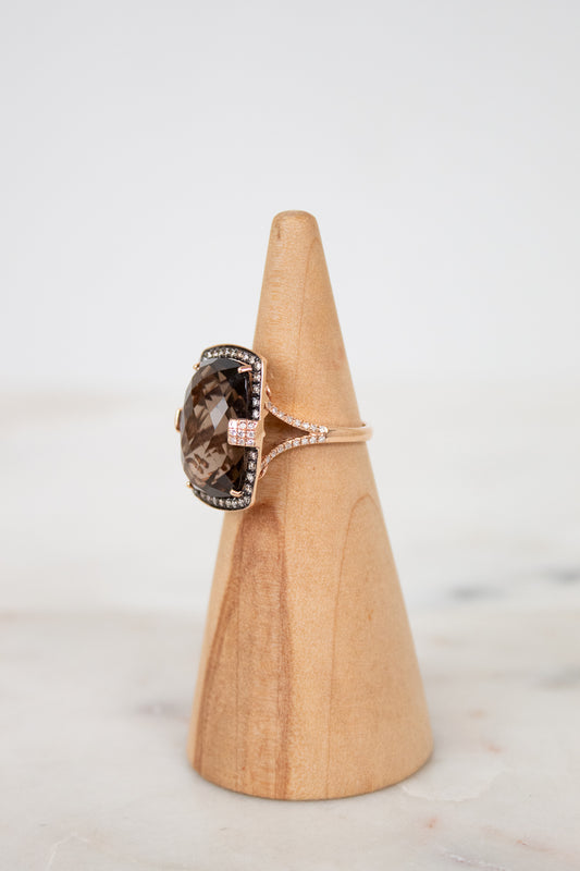 Ring with a brown gemstone on a wooden cone against a light background
