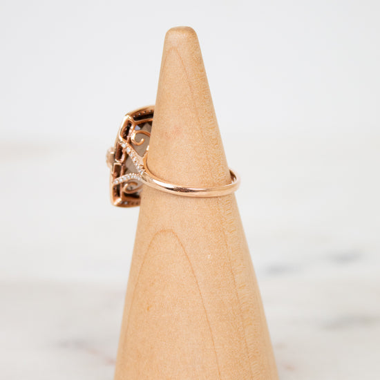 Rose gold ring on a wooden cone against a white background