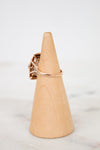 Rose gold ring on a wooden cone against a white background