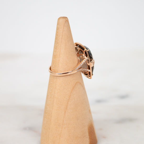 Wooden cone-shaped jewelry stand with a ring on a marble surface