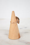 Wooden cone-shaped jewelry stand with a ring on a marble surface