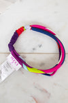 A multi-colored elastic headband by Pucci, featuring a vibrant spiral pattern of pink, purple, blue, red, and lime green, shown with its white paper tag on a white marble surface.