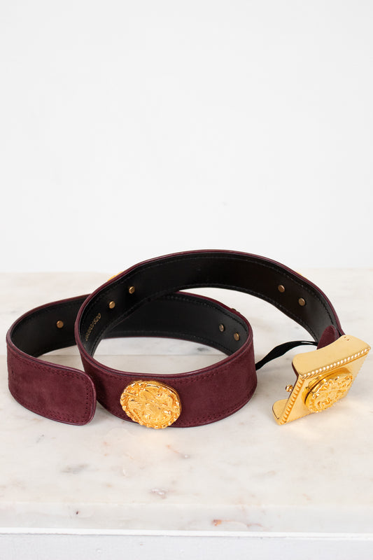 Burgundy belt with gold buckle on a light marble surface