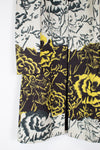 A close-up of a floral-patterned garment, likely a kimono or cardigan, featuring a split design with a black and gray floral print on the top and a black, gray, and bright yellow floral print on the bottom.