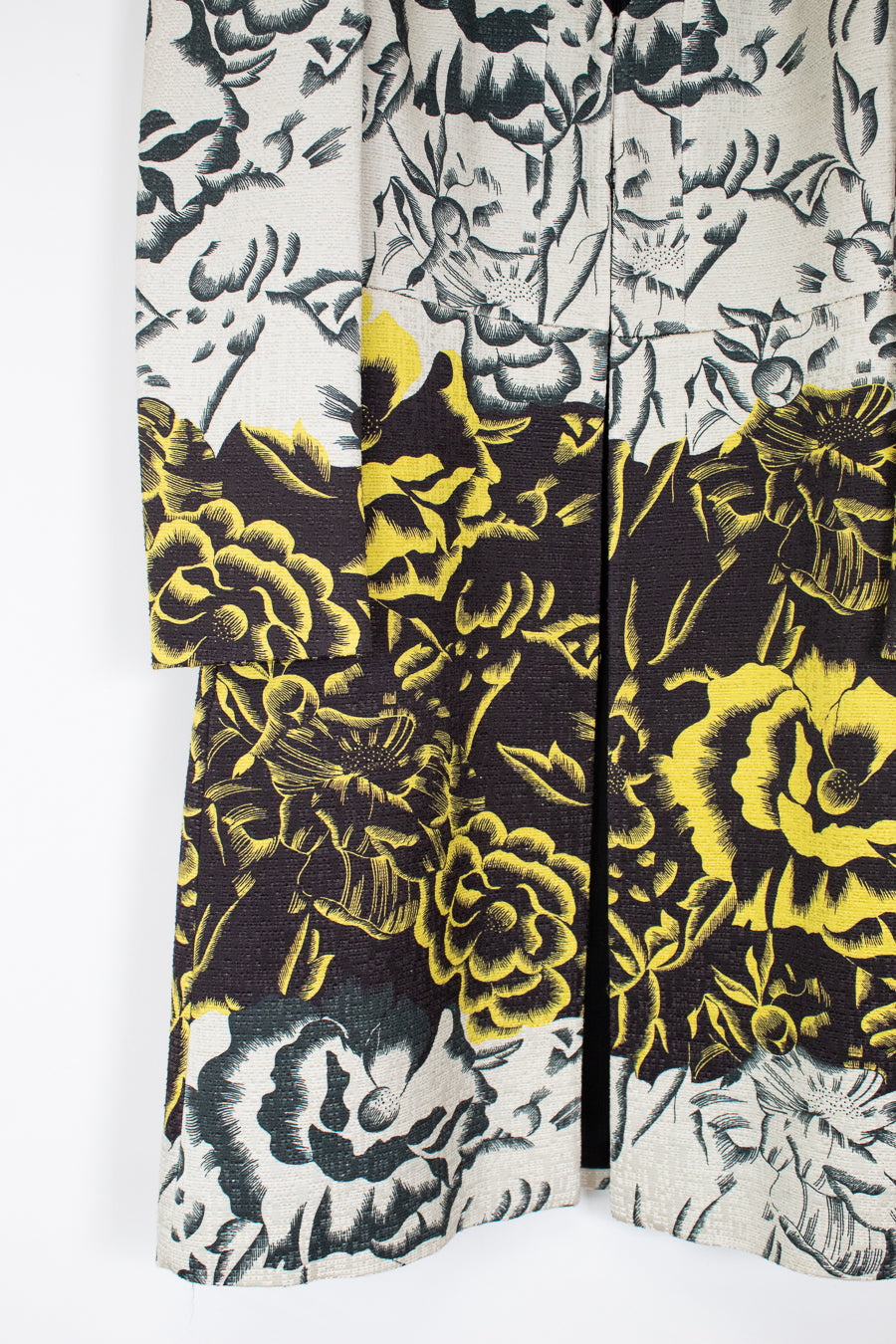 A close-up of a floral-patterned garment, likely a kimono or cardigan, featuring a split design with a black and gray floral print on the top and a black, gray, and bright yellow floral print on the bottom.