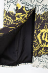 Close-up of a patterned kimono-style jacket with a black satin lining, featuring a bold yellow and black floral print on a white background.