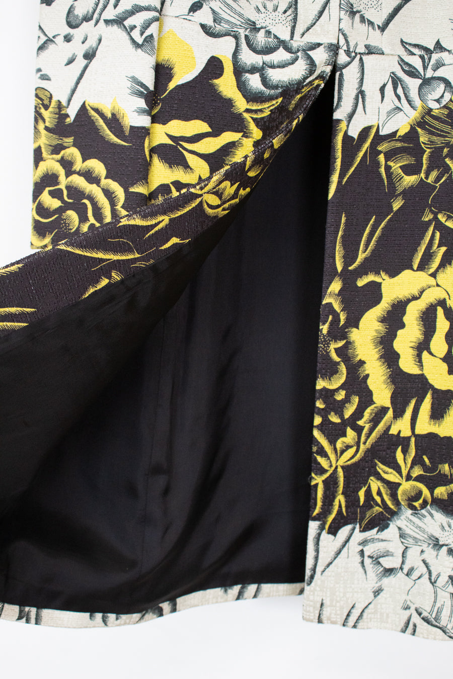 Close-up of a patterned kimono-style jacket with a black satin lining, featuring a bold yellow and black floral print on a white background.